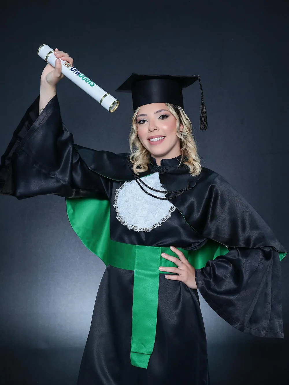Dra. Gabrieli Sobral em vestimenta de formatura, segurando o diploma